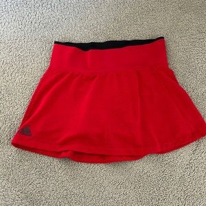 Red tennis skirt. High waisted. Hugs waist. Shorts connected underneath. 🥰